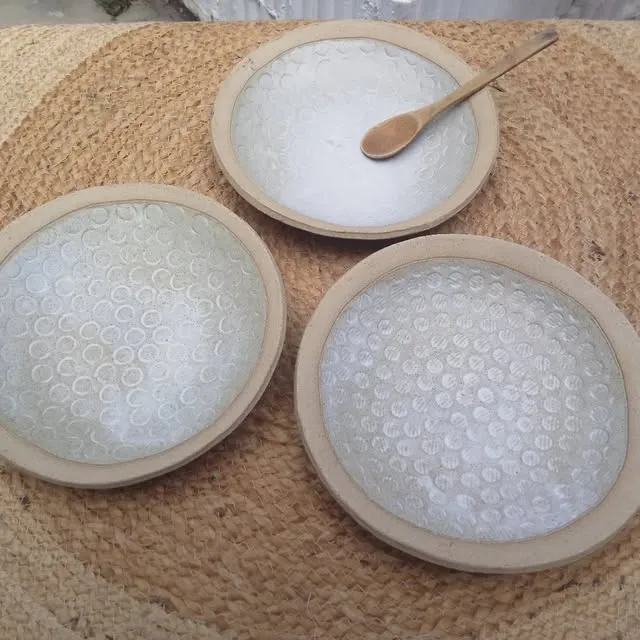 Trois assiettes creuses à l’intérieur blanc imprimé de fleurs, avec une cuillère en bois