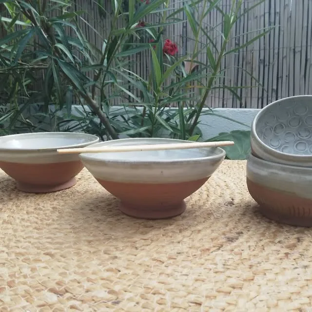Bols bicolores, extérieur en terre brute et intérieur émaillé, sur un tapis de raphia au jardin